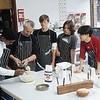 Fontbonne University > Teenage boys (13-15) in kitchen, one helping teacher with cake mix
